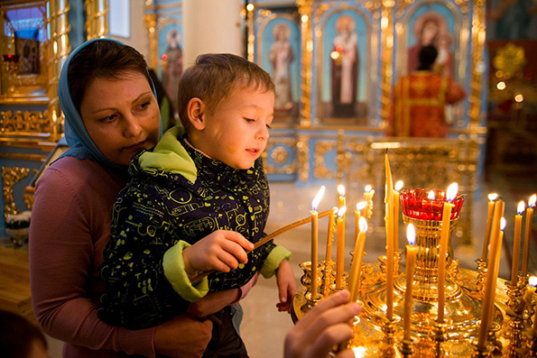Ребенок ставит свечку в храме